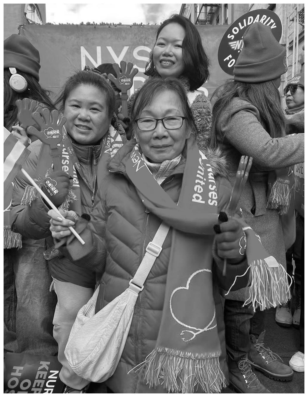 Black-and-white photo of nurses at a solidarity event holding signs and foam hands.